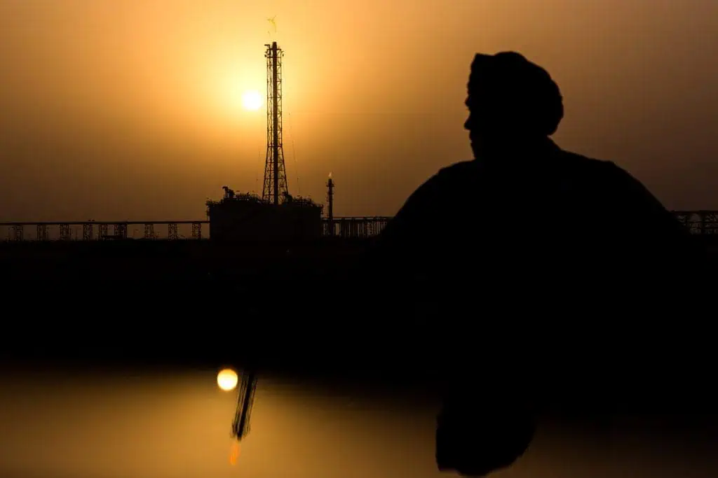 Silhouette of a person and oil rig at sunset in Dubai.