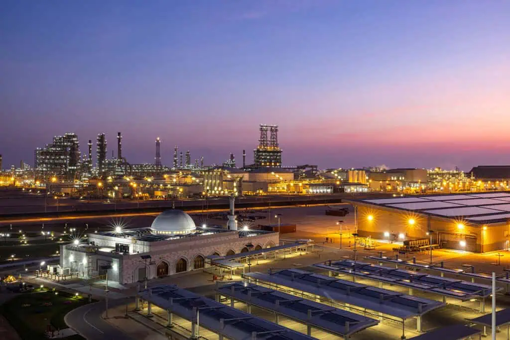Industrial oil and gas facilities in Dubai at sunset with city skyline.