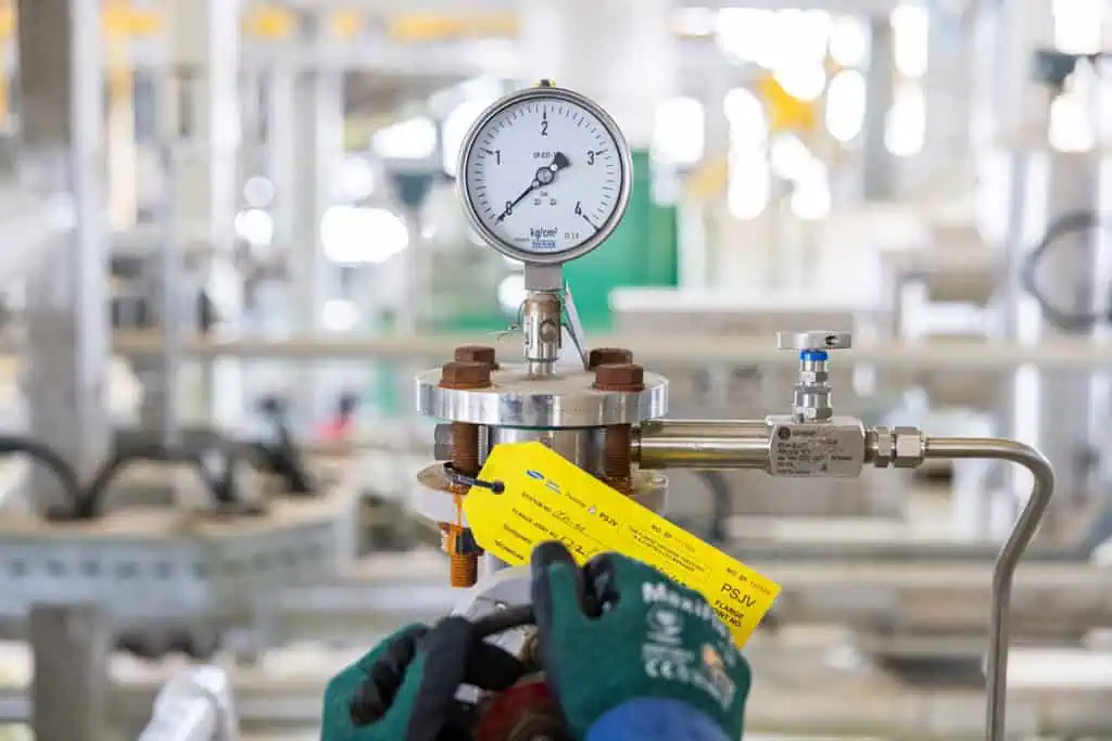 Close-up of pressure gauge in oil and gas industrial setting.