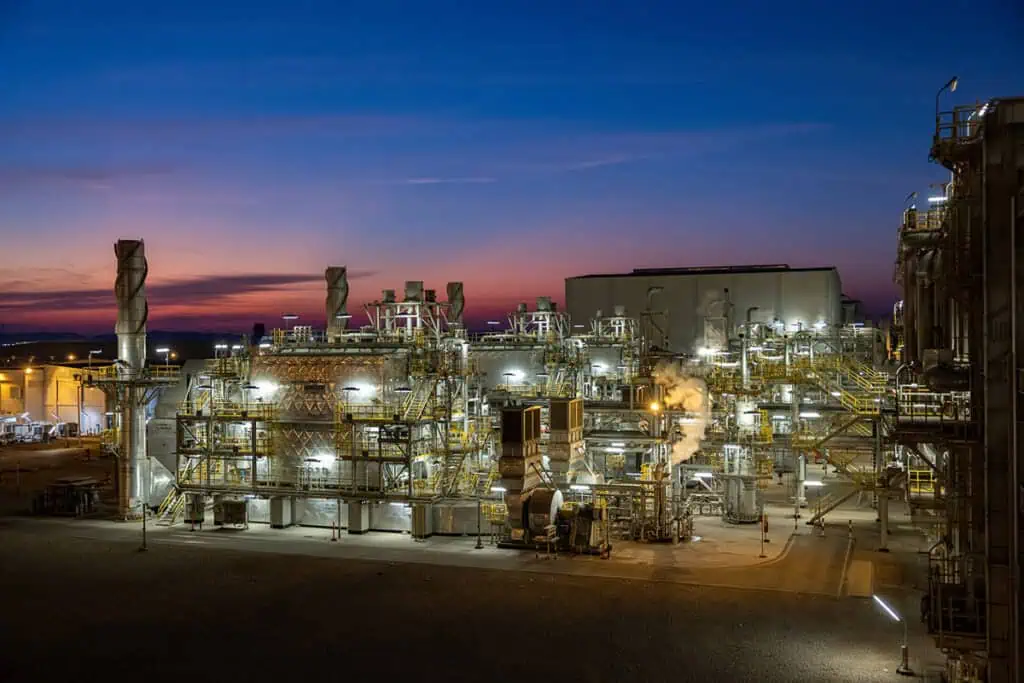 Oil and gas industrial plant in Dubai during sunset with illuminated equipment.