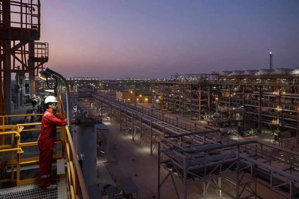 Oil and gas worker inspecting equipment at sunset in Dubai industrial site.