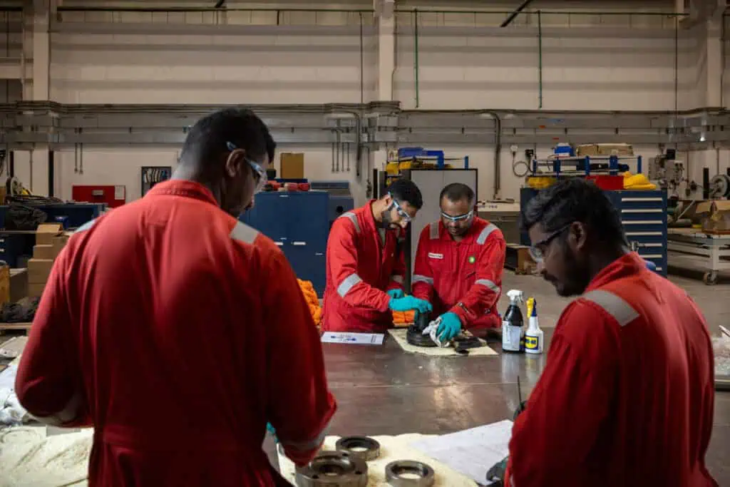 Workers in red uniforms collaborating in an industrial workshop.