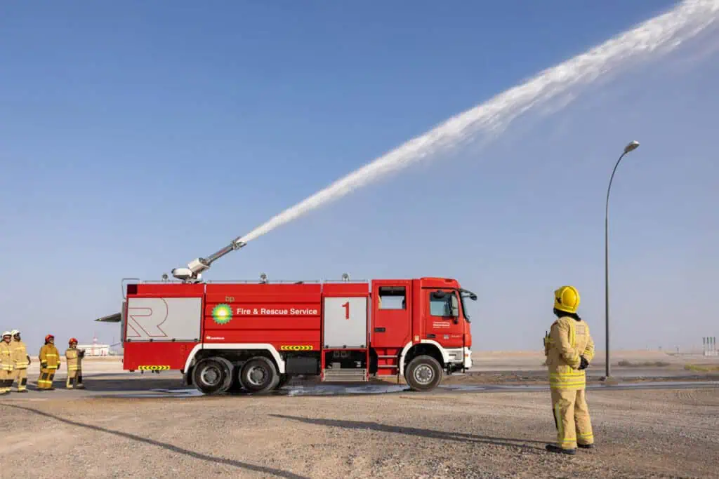 Firefighters in Dubai practicing firefighting with a water hose on a clear day.