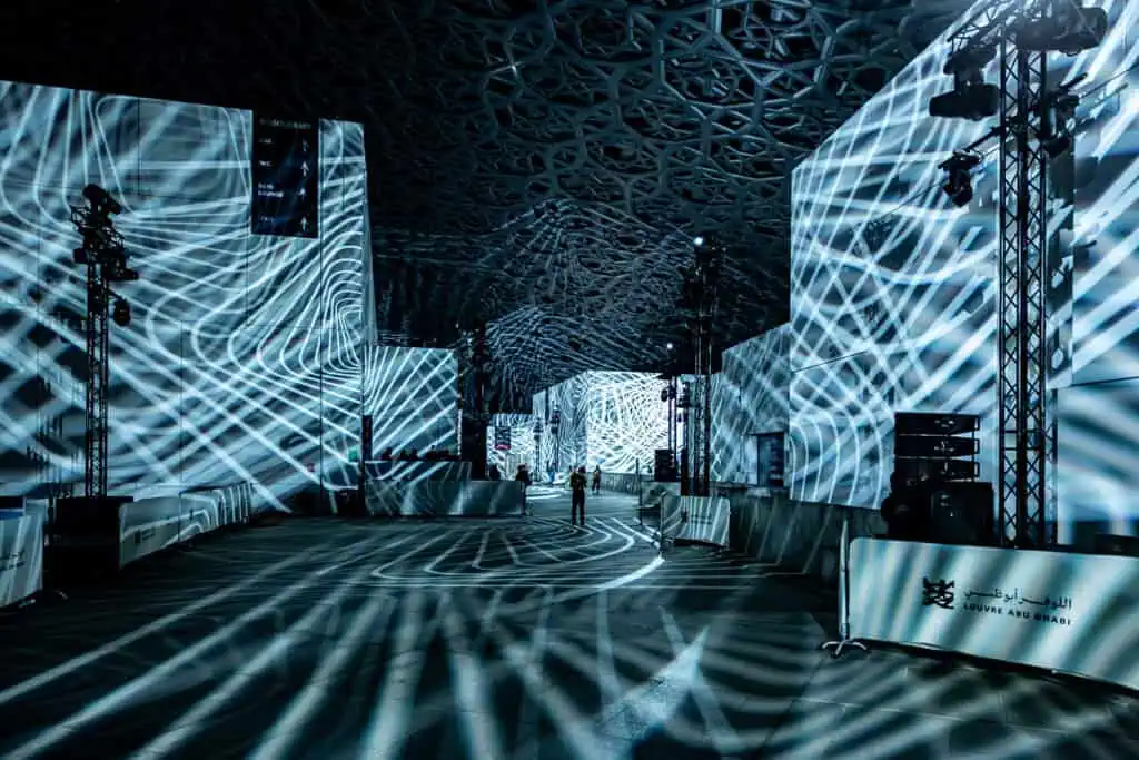 Modern corporate event space with dynamic light projections at Louvre Abu Dhabi.